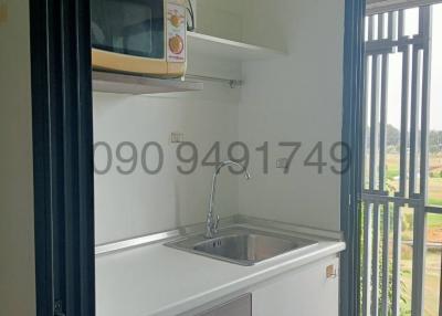 Compact modern kitchen with stainless steel sink, microwave, and ample daylight