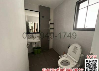 Modern bathroom with white tiles, toilet, and mirror