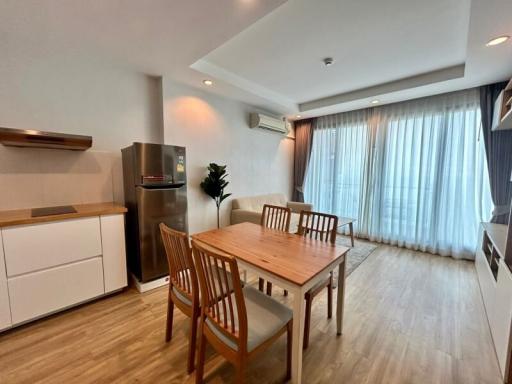 Modern kitchen with dining area, wooden table, chairs, and stainless steel refrigerator