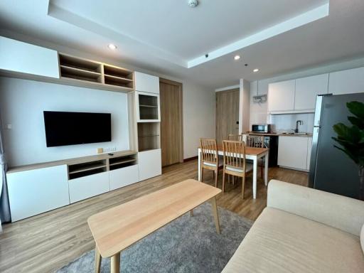 Modern living room with open kitchen design, including dining area and plenty of natural light