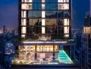 Illuminated modern high-rise building at dusk with visible interior details and pool