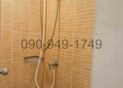 Wall-mounted electric shower unit in a tiled bathroom