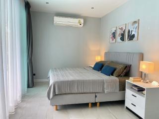 Modern bedroom with a queen-size bed, light-colored decor, and artwork