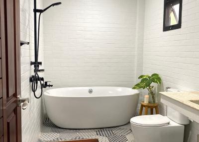 Modern white bathroom with freestanding tub, walk-in shower, and elegant tiling