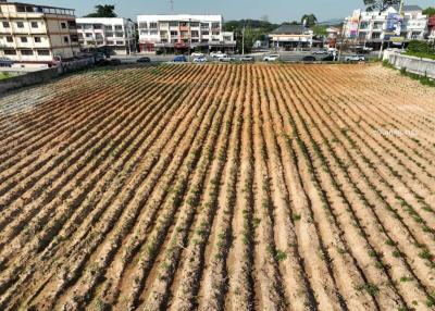 Aerial view of a plowed field with clear furrows, with urban development in the background