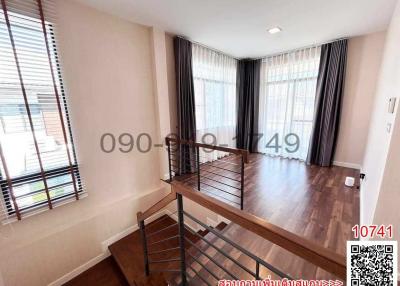 Spacious and well-lit living room with large windows and hardwood flooring.