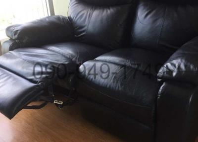 Black leather recliner sofa in a living room with natural light