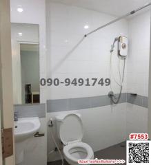 Modern white tiled bathroom with shower, toilet, and sink