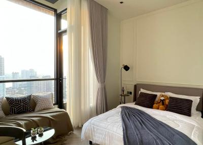 Modern bedroom with a view, featuring a large bed, floor-to-ceiling window, and tasteful decor
