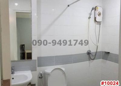Modern white tiled bathroom with shower, toilet and sink