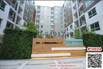 Exterior view of a modern apartment building entrance with greenery