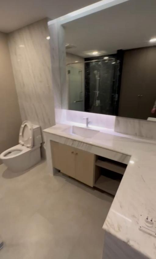 Modern bathroom interior with illuminated mirror and glass shower enclosure