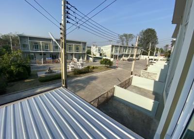 View from a balcony overlooking a residential area with townhouses and electrical lines