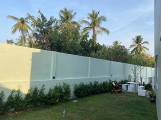 Lush green backyard with tall surrounding wall and tropical palm trees