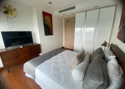 Spacious bedroom with a large bed, reflective mirrored closet, and a mounted TV