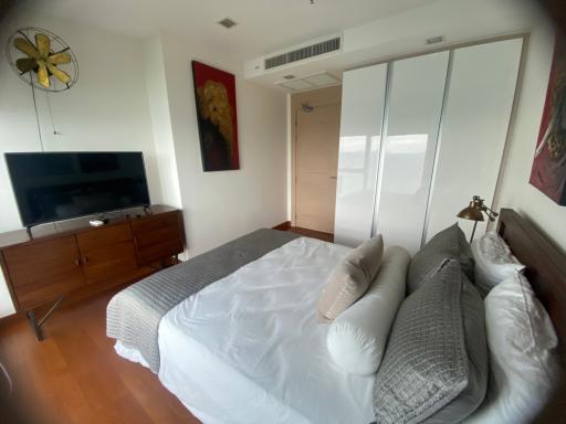 Spacious bedroom with a large bed, reflective mirrored closet, and a mounted TV