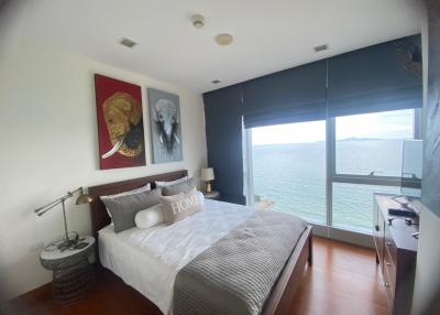 Spacious bedroom with ocean view, elegant decor, and natural light
