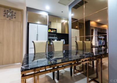 Modern dining area with marble table and kitchen in the background
