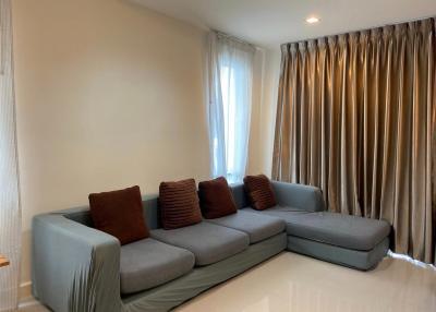 Spacious living room with large sectional sofa and elegant curtains