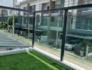 Balcony view overlooking modern townhouses with artificial grass and glass balustrade