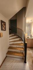 Elegant staircase with wooden steps and wrought-iron railing in a well-lit home interior