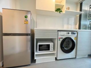 Modern kitchen with stainless steel refrigerator, built-in microwave, and front-loading washing machine