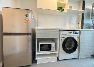 Modern kitchen with stainless steel refrigerator, built-in microwave, and front-loading washing machine
