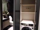 Modern bathroom with integrated laundry space, featuring a washing machine, marble flooring, and sophisticated dark tones