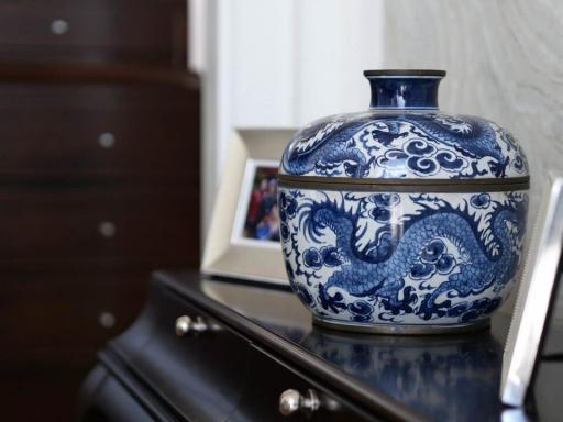 Decorative blue and white porcelain jar on a bedroom dresser with a photo frame in the background