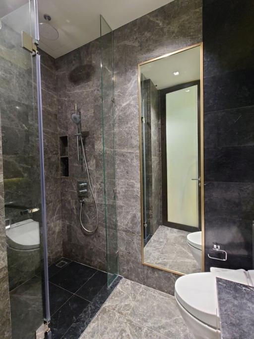 Modern bathroom with walk-in shower and dark stone tiles