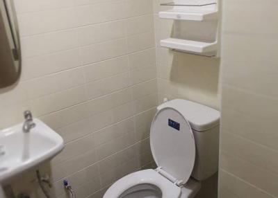 Small bathroom with white toilet and wall-mounted storage shelves