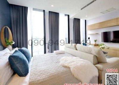 Modern bedroom with integrated living space, large bed, and expansive windows