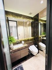 Modern, well-lit bathroom with reflective surfaces and green plants