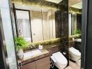 Modern, well-lit bathroom with reflective surfaces and green plants