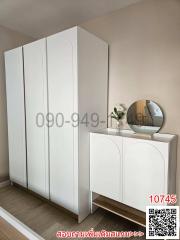 Modern bedroom with a large white wardrobe and a stylish dresser with a round mirror