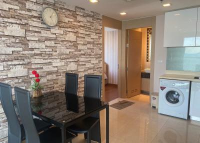 Modern living area with dining set, brick accent wall, and integrated laundry