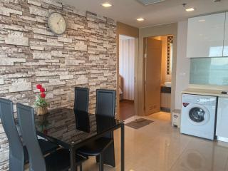 Modern living area with dining set, brick accent wall, and integrated laundry