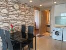 Modern living area with dining set, brick accent wall, and integrated laundry