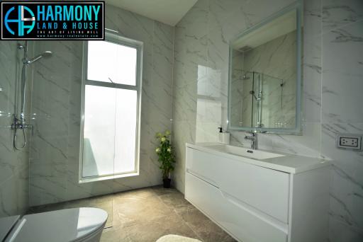 Modern bathroom with marble walls and floor, shower cabin, and vanity area