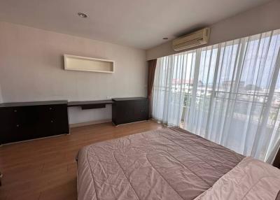 Spacious bedroom with large bed, wooden flooring, and ample natural light