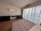 Spacious bedroom with large bed, wooden flooring, and ample natural light