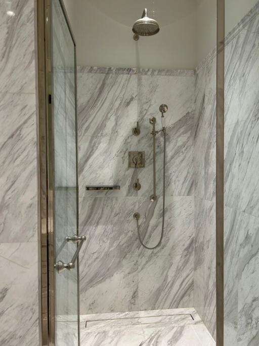 Elegant bathroom with marble walls and glass shower cabin