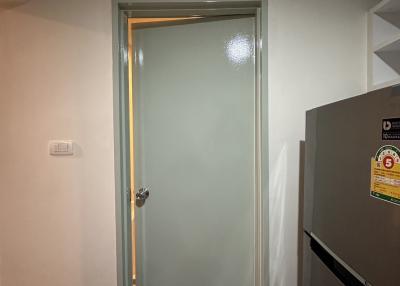 Interior door leading to another room with frosted glass insert and adjacent refrigerator