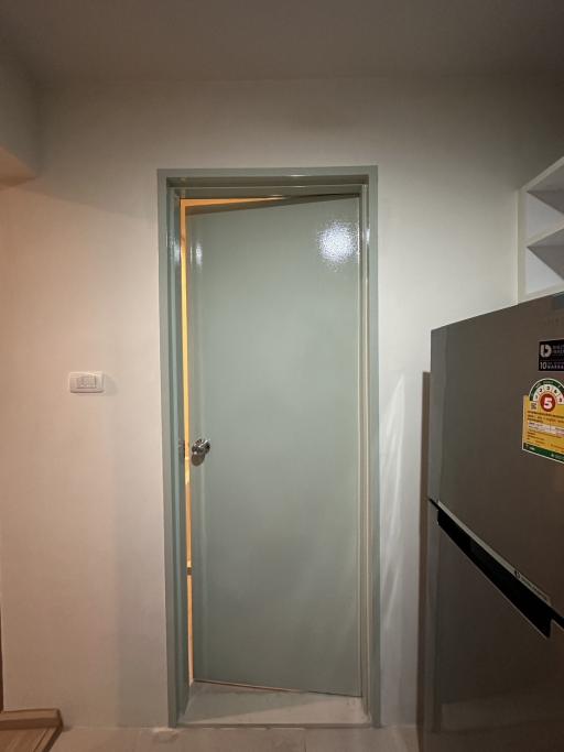 Interior door leading to another room with frosted glass insert and adjacent refrigerator