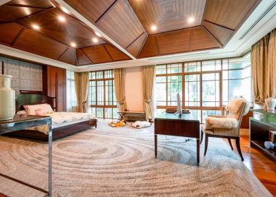 Spacious bedroom with wooden ceiling and floor, large windows, and elegant furniture
