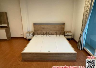 Spacious bedroom with large bed frame and wooden flooring
