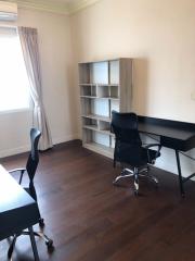 Home office with desk, chair, and bookshelf on wooden flooring