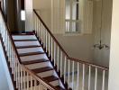 Elegant curved staircase with white balusters and wooden steps leading to an upper level
