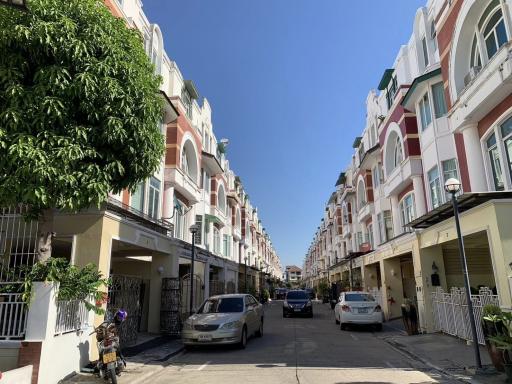 Residential street with row houses and parked cars under a clear blue sky