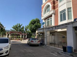 Front view of a residential building with parked cars and gated entrances